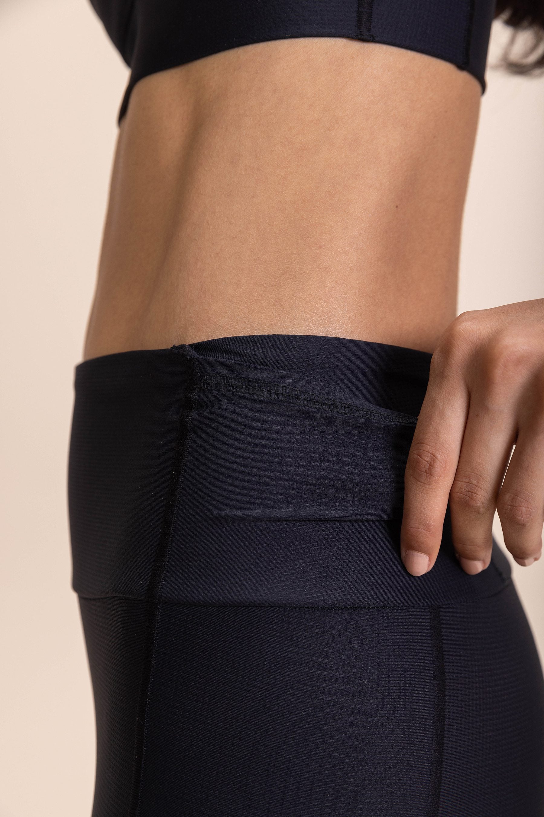 Close-up of a model wearing the "Legging 6 Pockets Speed" in dark fabric, highlighting one of the six pockets.