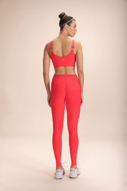 Woman wearing red "Legging 6 Pockets Speed" and matching sports bra, standing with her back to the camera.